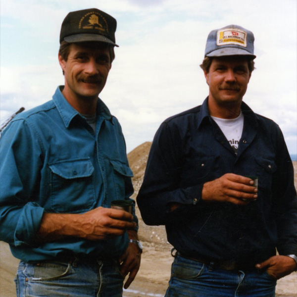 Historic miners standing near heavy equipment